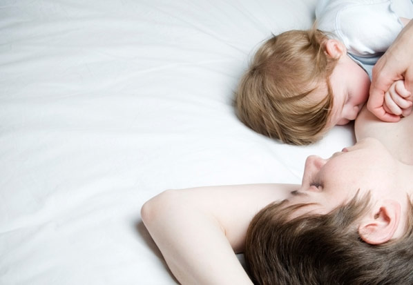 Eine Mutter die mit ihrem Kind im Bett liegt und dieses stillt