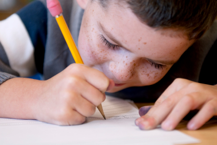 Bub mit Sommersprossen, Bleistift in der Hand, zeichnet