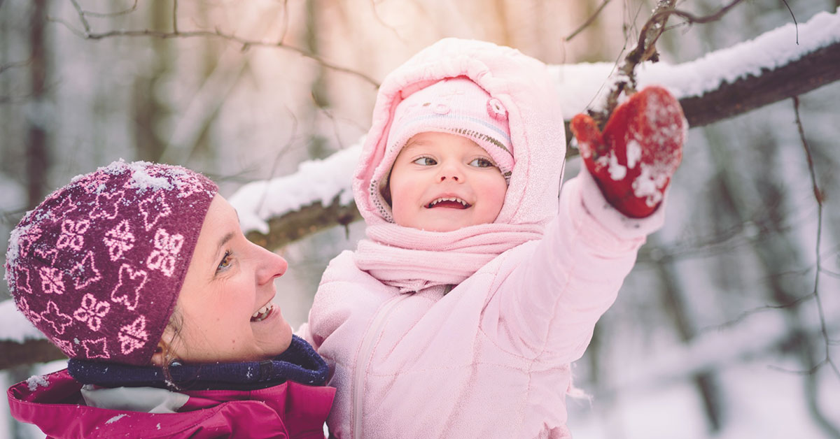 Mutter und Kleinkind bei einem Spaziergang im Winter-Wald