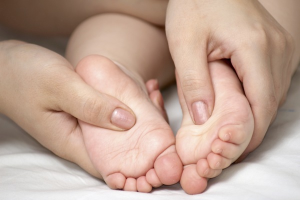 Babyfüsse die von einer Mutter massiert werden